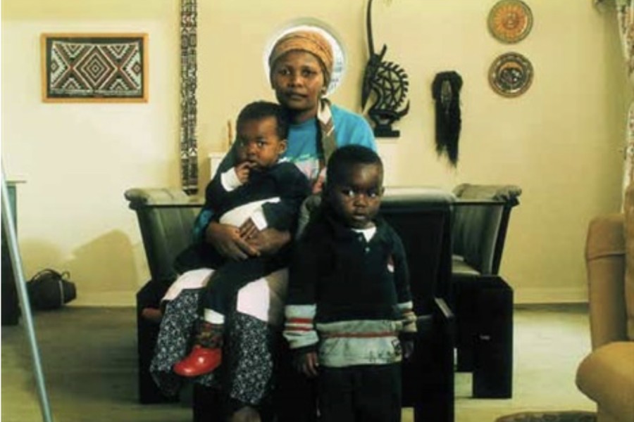 "Victoria Cobokana, housekeeper, in her employer’s dining room with her son Sifiso and daughter Onica, Johannesburg, June 1999. Victoria died of AIDS 13 December 1999, Sifiso died of AIDS 12 January 2000, Onica died of AIDS in May 2000." by David Goldblatt