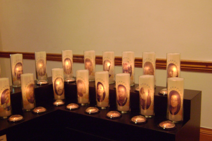 Candles bearing portraits in Jean Carlomusto’s *Offerings*