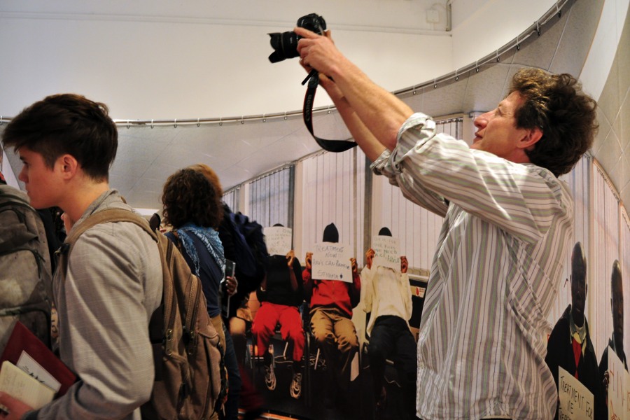 Gideon Mendel photographing visitors inside *The Harsh Divide and Through Positive Eyes*