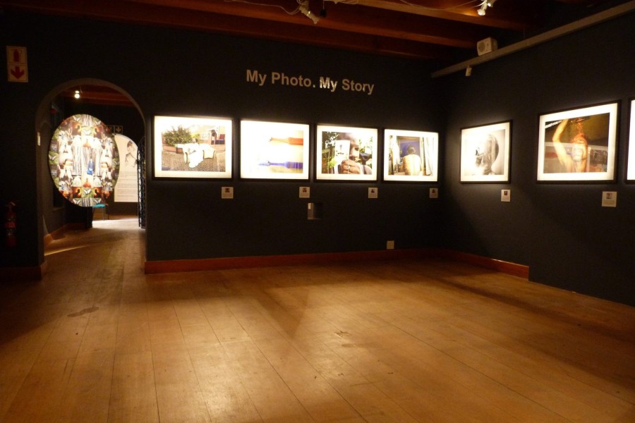 Gallery view with photographs and a photographic mandala visible through the left portal into the next gallery