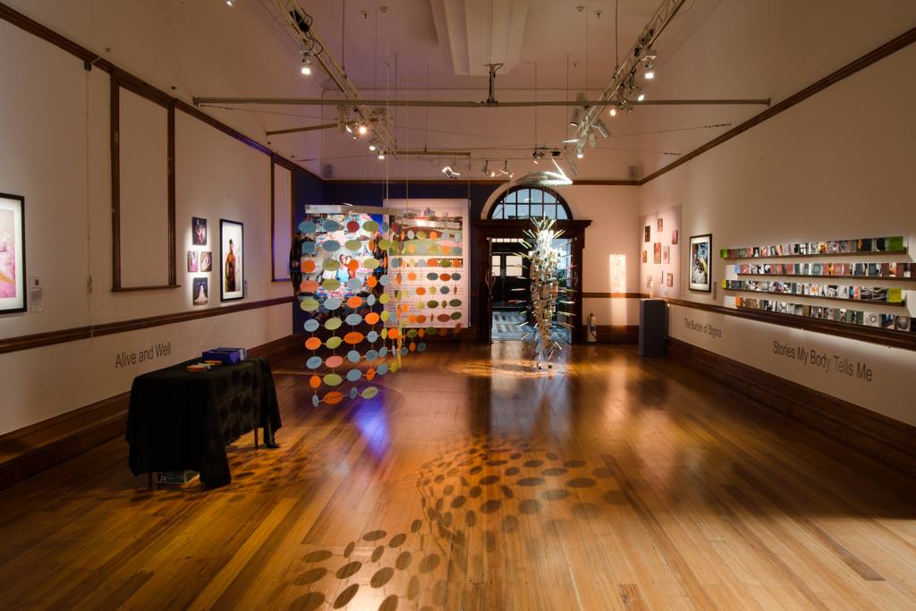 Multiple works by Through Positive Eyes artivists displayed in the gallery