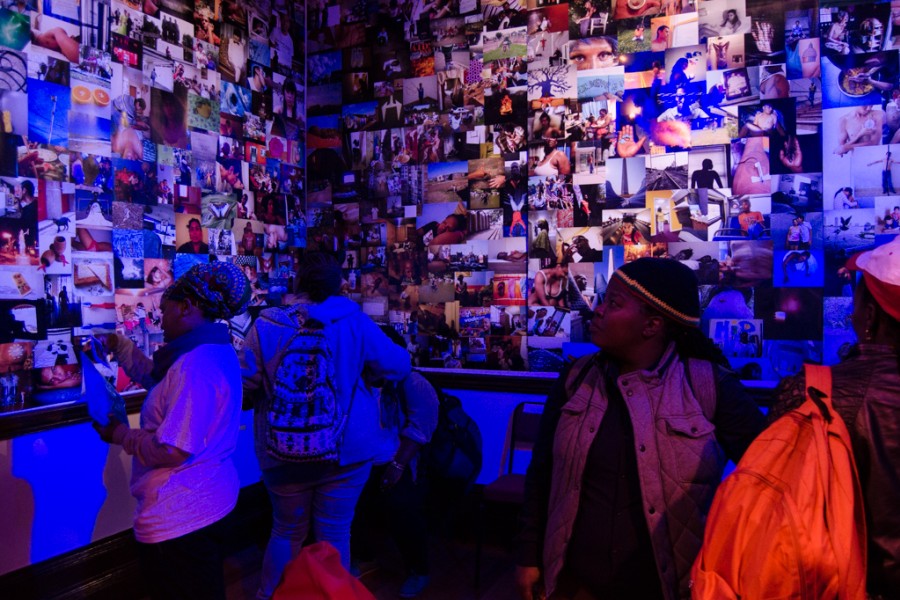 Visitors among photographic wallpaper under blacklight and spotlights in the Banishing Stigma Room