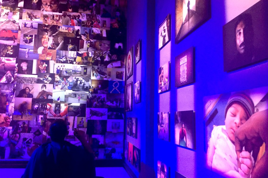 Visitor viewing photographic wallpaper and prints under pink and blue lighting in the Banishing Stigma Room