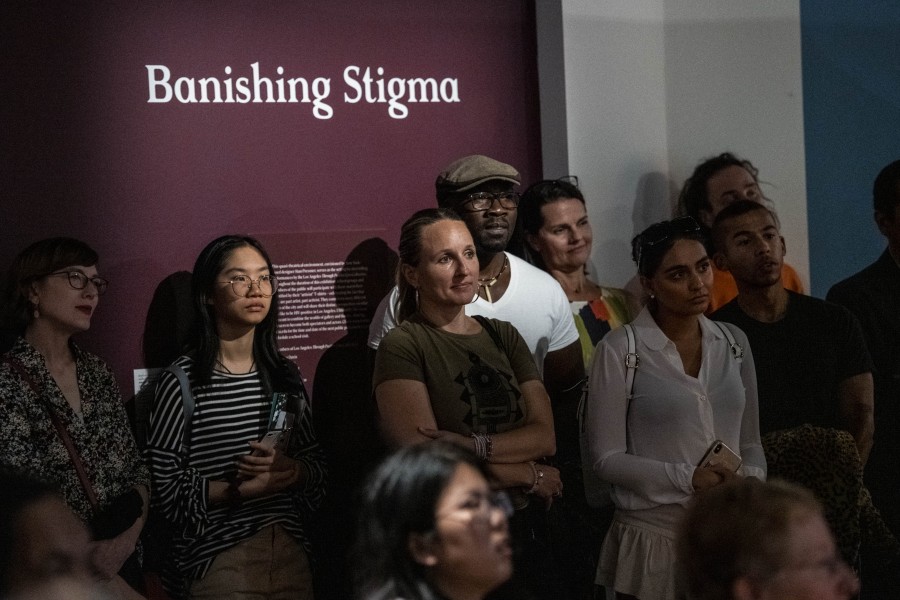 Standing audience watching an artivist perform beneath the Banishing Stigma Room title wall