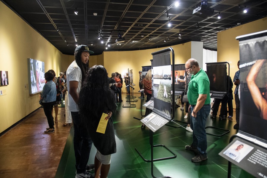 Visitors viewing artivist photographs, stories, and portraits by Gideon Mendel