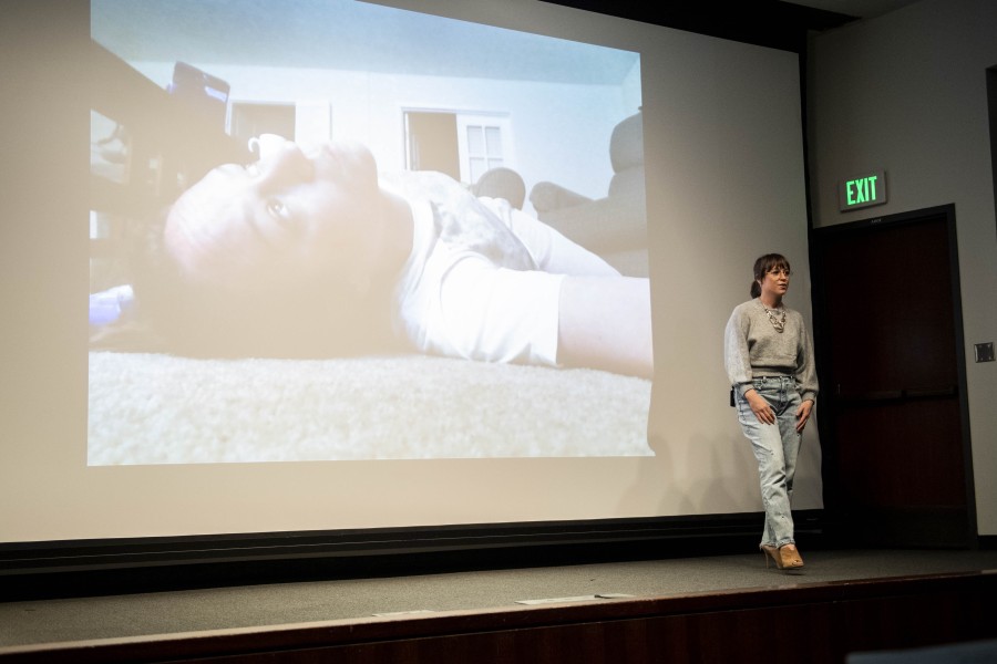 Kelly storytelling before an audience with one of her photographs projected behind her