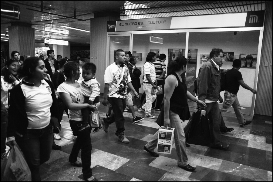 A crowd moving past the exhibition while some people view photographs and stories